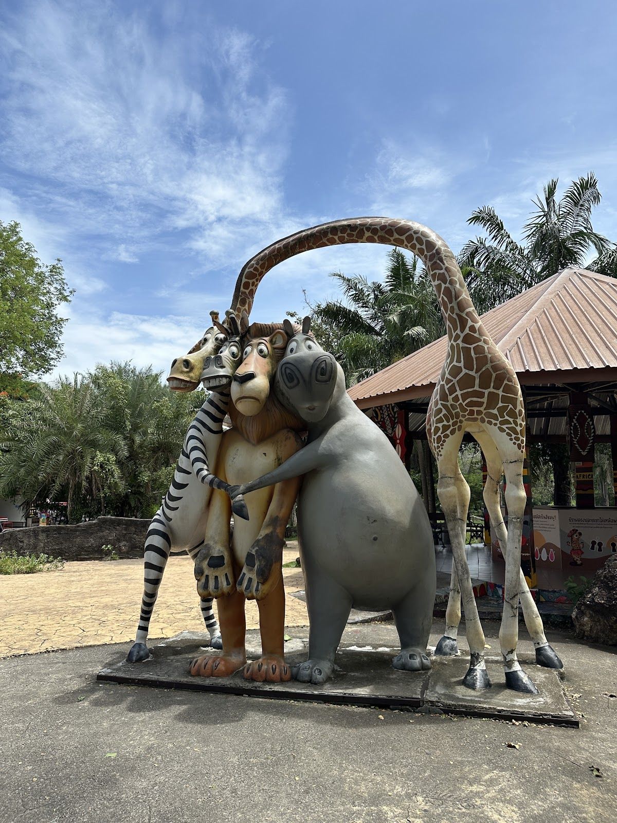 A keeper feeds two Asian elephants through a fence at Khao Kheow Open Zoo, the animals reaching out with their trunks for bundles of green leaves