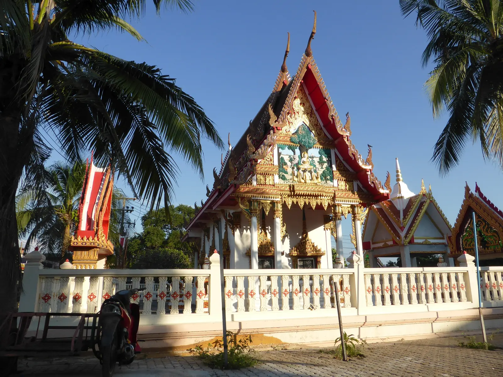A pier on Koh Larn with a welcome sign and longtail boats alongside