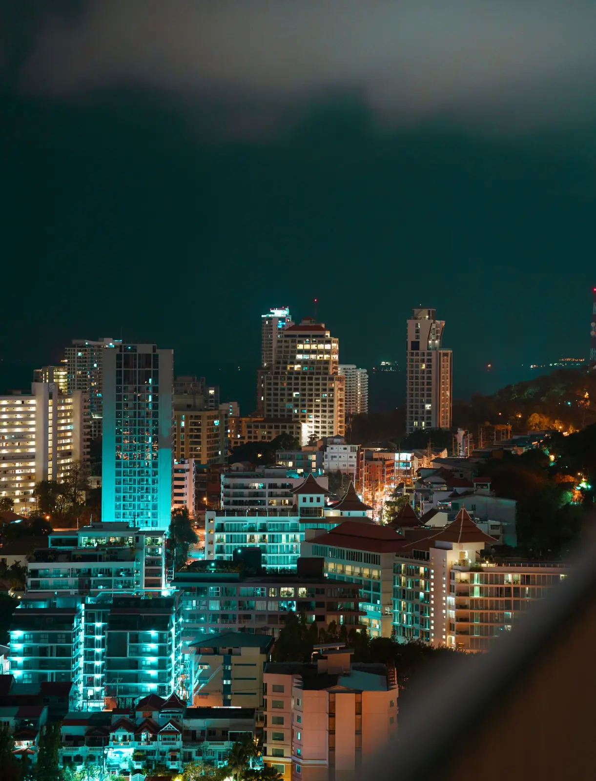 Illuminated towers in Pattaya at night against a dark sky