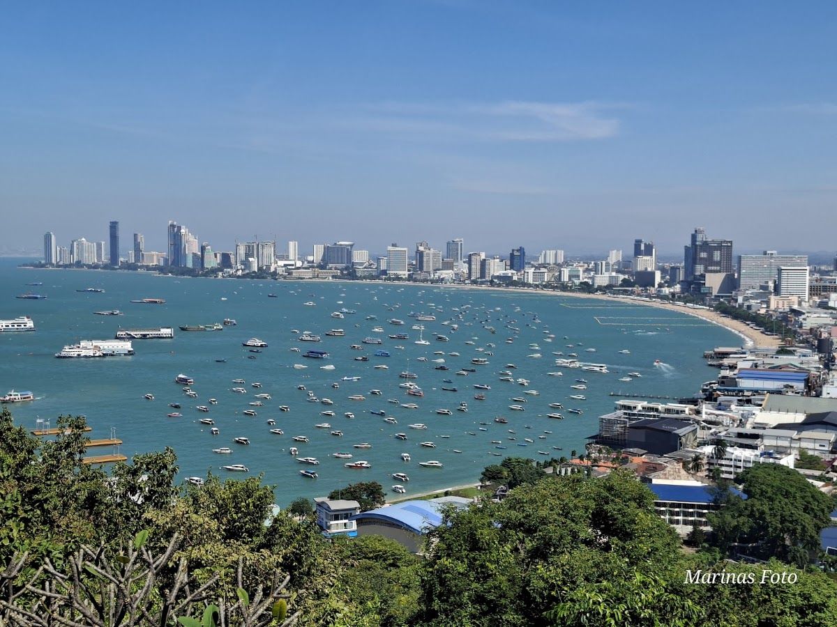 Panoramic view of Pattaya Bay and city skyline from Pratumnak Hill viewpoint, with dozens of boats on the turquoise water below