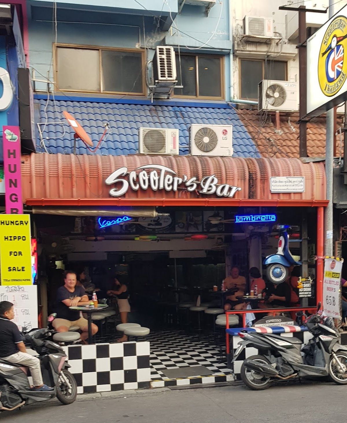 Scooter's Bar on Soi Buakhao Pattaya at night — an open-fronted beer bar with neon Vespa and Lambretta signs glowing on the facade